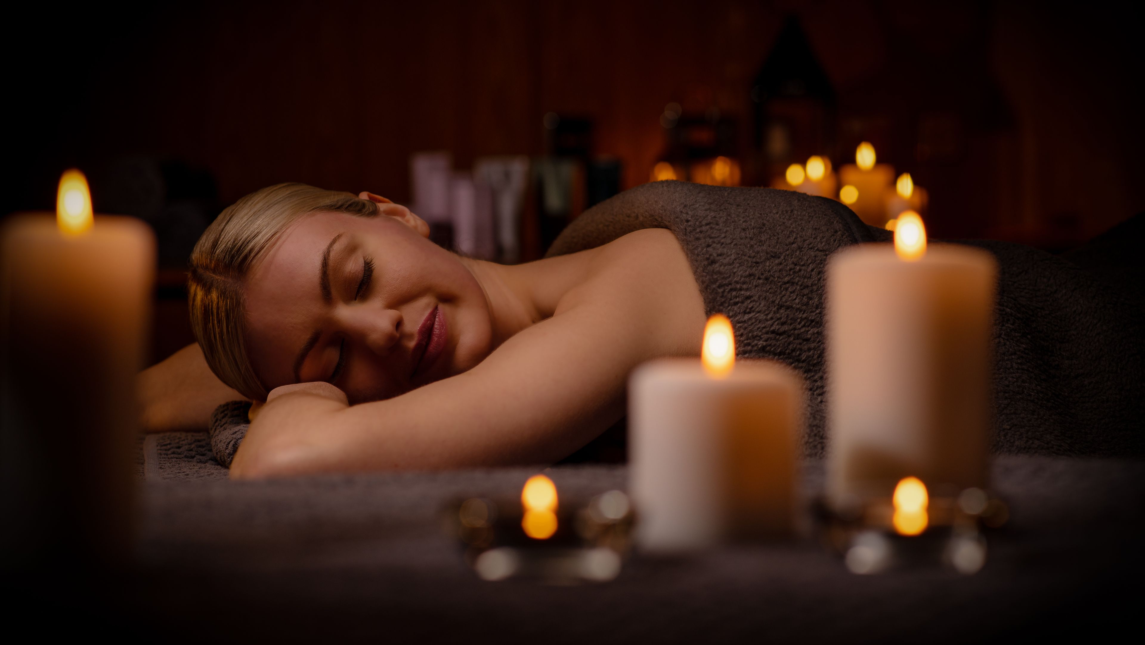 A lady relaxing in the treatment room, surrounded by candles